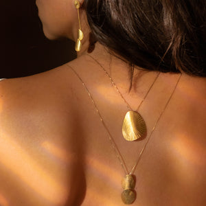 Close-up of a person wearing gold necklaces and earrings with a warm light effect.