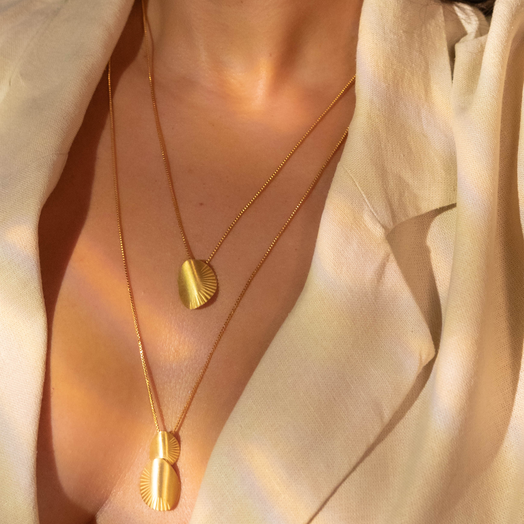 Close-up of a person wearing gold jewelry including earrings and necklaces.