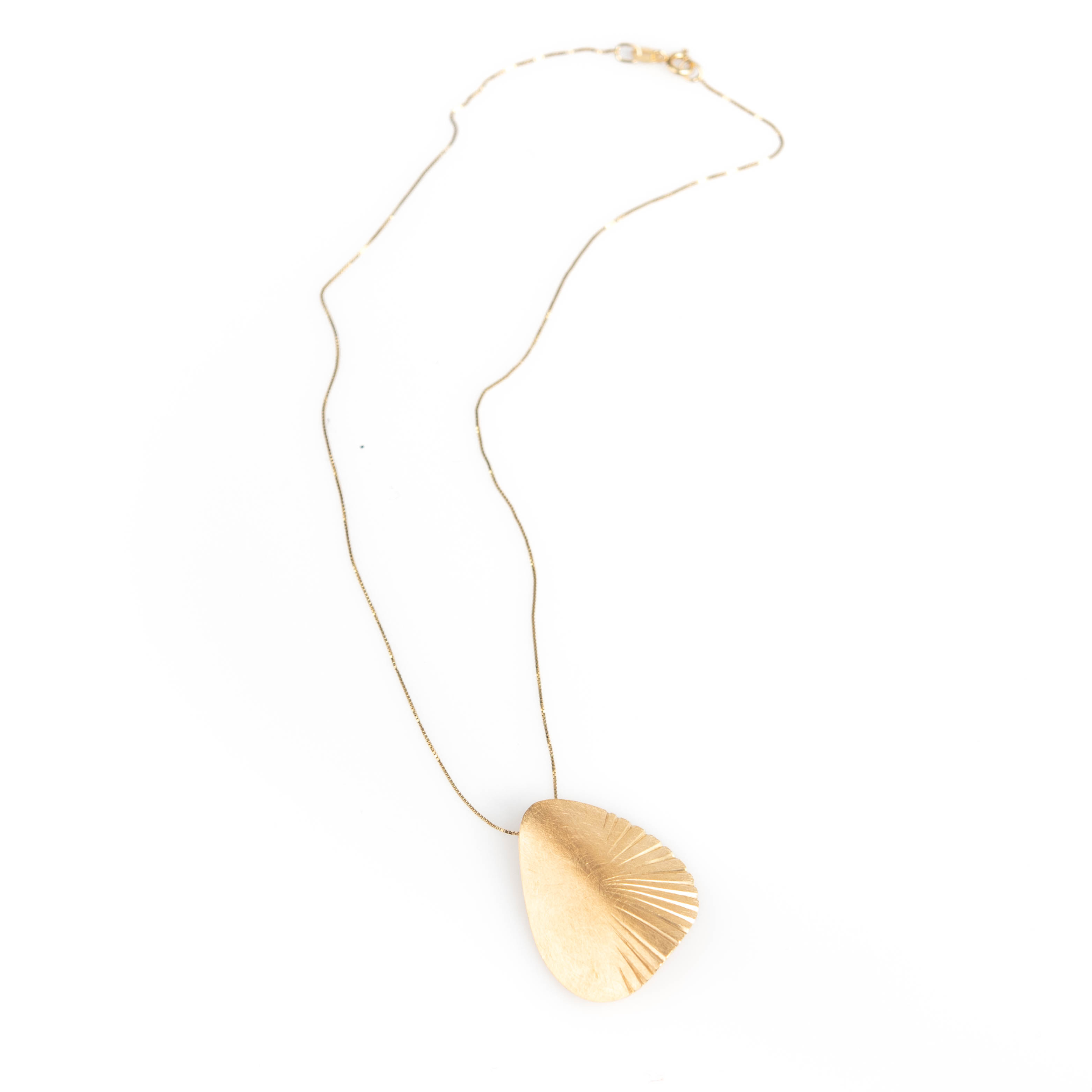 Gold necklace with a leaf-shaped pendant on a white background