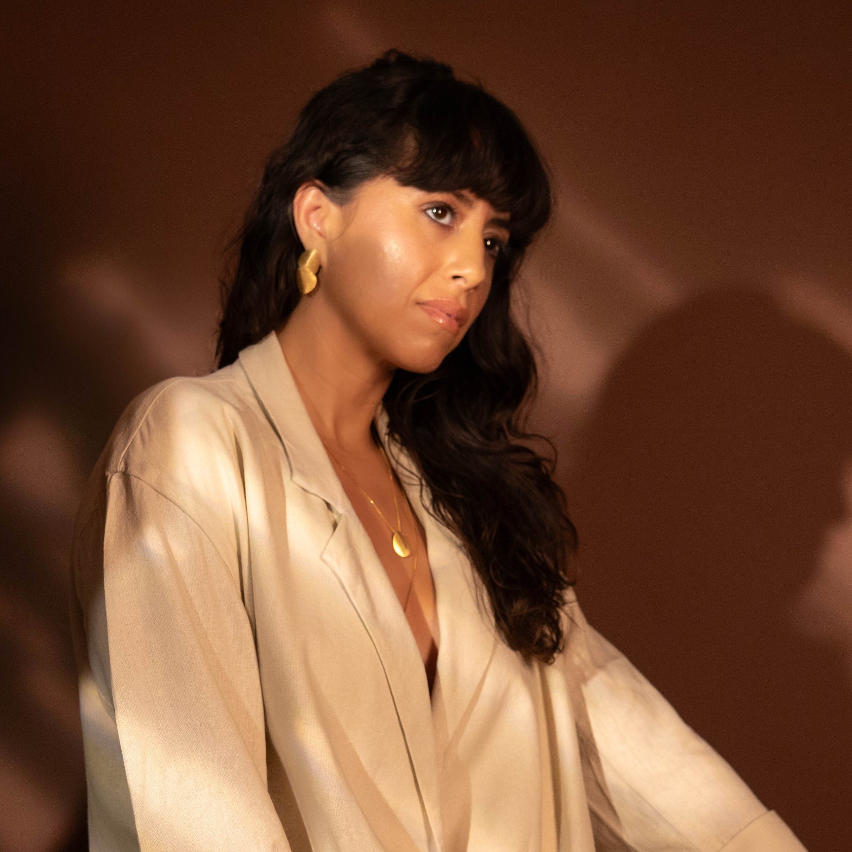 Woman wearing a white outfit with black buttons against a dark background