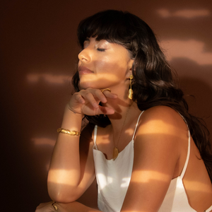 Woman in a white dress sitting against a dark background with a warm glow