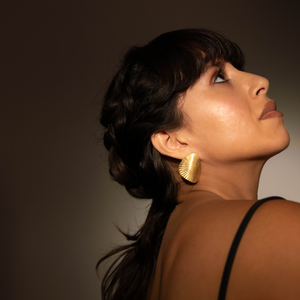 Woman wearing gold earrings against a neutral background