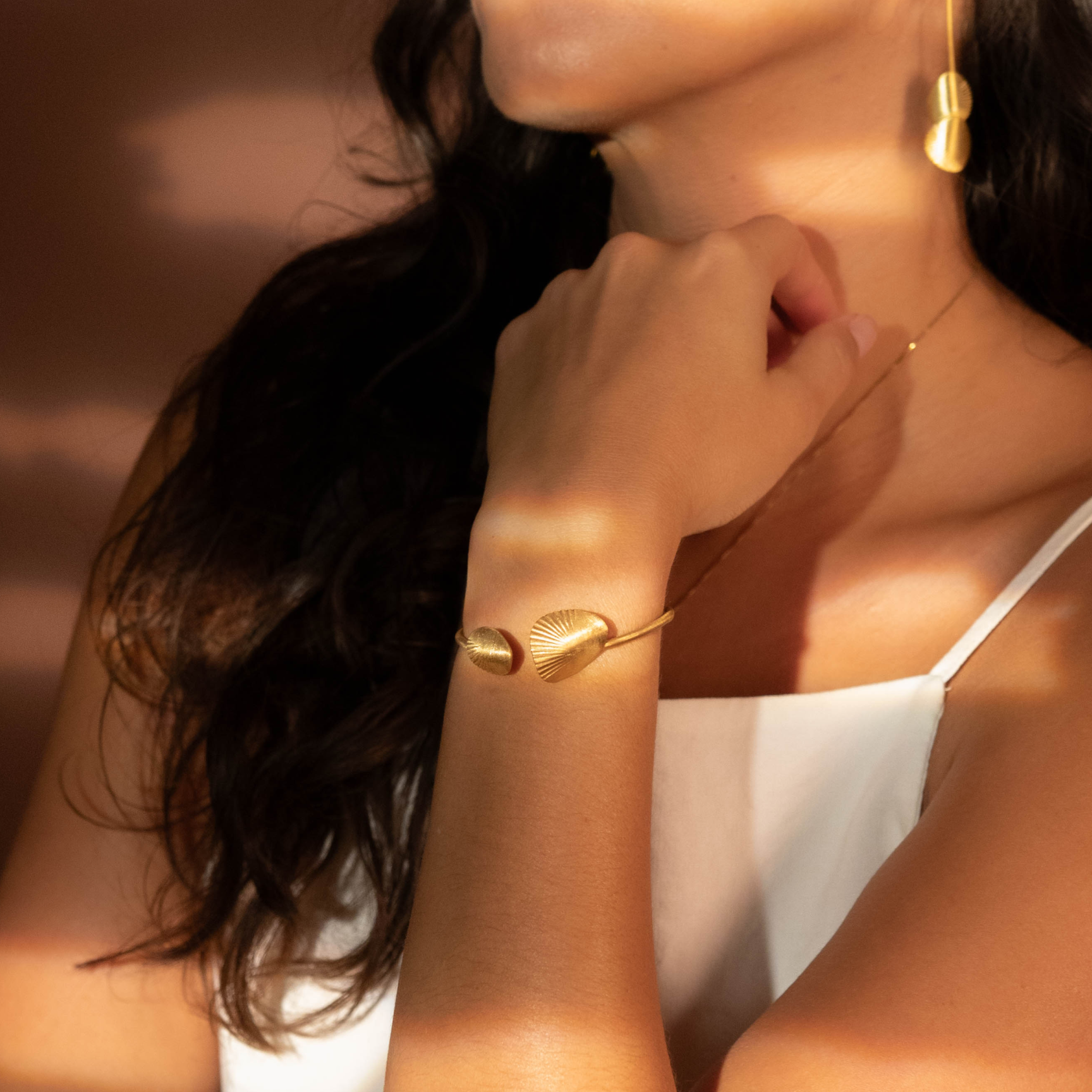 A person wearing a gold-colored bracelet on their wrist.